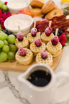 some waffles and fruit are on a table with other food items around them