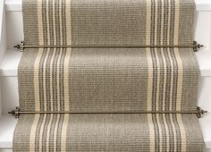 a stair case with two beige and black striped rugs on the side of it