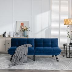 a blue couch sitting on top of a white floor next to a table and lamp