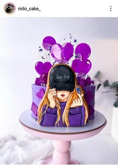 a purple cake with a woman's face on it and balloons in the background