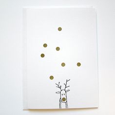 a white card with a drawing of a reindeer on it's face and gold dots in the background