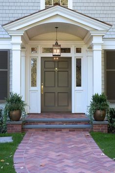 the front entrance to a house with two planters on either side