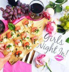 a person holding a tray with food on it next to some flowers and wine glasses