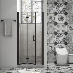 a bathroom with black and white tiles on the wall, shower stall and toilet in the corner