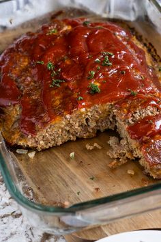 meatloaf in a glass casserole dish on a wooden cutting board with a slice cut out