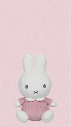 a white stuffed rabbit sitting in front of a pink background