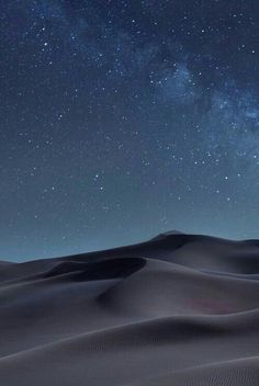 the night sky is filled with stars above sand dunes