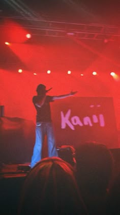 a man standing on top of a stage in front of a red lit sign that says kani