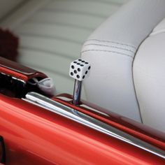 the dice is sitting on top of the red car's headrests and seat