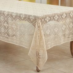 a table covered with a white crochet doily sitting on top of a tile floor