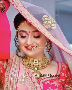 a woman wearing a pink and gold bridal outfit, with jewelry on her face