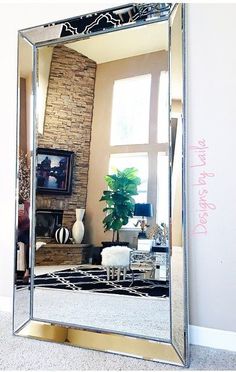 a large mirror sitting on top of a floor next to a living room table and chair