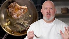 a man standing in front of a frying pan filled with food