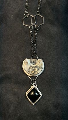 This is a grey Jasper crescent moon complimented by an diamond shaped Obsidian set in sterling silver. It's on a 26" gunmetal rolo chain with hexagon details. Elegant Black Hand Forged Necklace, Gray Sterling Silver Dangle Jewelry, Sterling Silver Gray Dangle Jewelry, Unique Black Jewelry With Moon Phase, Artisan Crescent Jewelry Hand Forged, Unique Black Moon Phase Jewelry, Artisan Hand Forged Crescent Jewelry, Artisan Hand-forged Crescent Jewelry, Silver Obsidian Pendant Necklace