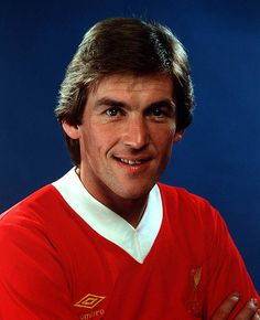 an old photo of a man wearing a red shirt and holding his arms crossed in front of him