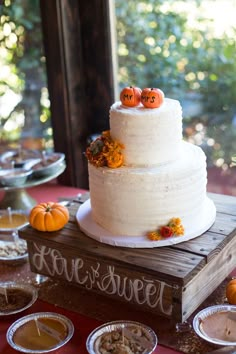 a three tiered cake with pumpkins on top is sitting on a wooden box