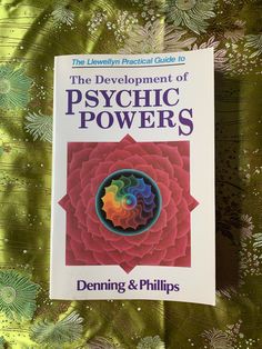 the development of psychic powers by denning and phillips book on green fabric with white flowers