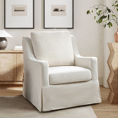 a white chair sitting in a living room next to a table with a vase on it