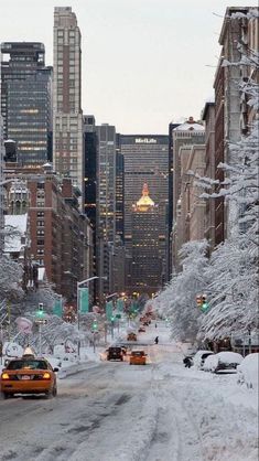 the city street is covered in snow with cars driving down it