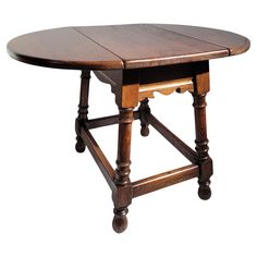 an old fashioned wooden table with wheels on one leg and two leaves on the other