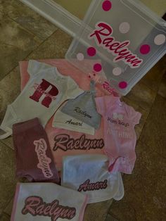 some baby clothes are laying on the floor next to a plastic bag with pink and white designs