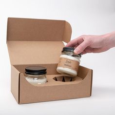 a person is opening a box with two jars in it and the lid opened to show what's inside