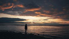 a person standing on the beach at sunset