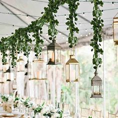 an outdoor wedding with lanterns and greenery hanging from the ceiling, along with candles