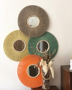 a vase filled with flowers on top of a wooden table next to three circular mirrors