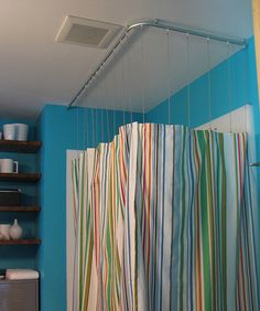 a bathroom with blue walls and striped shower curtain hanging from the ceiling, next to a toilet