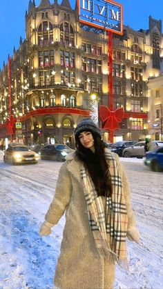 a woman standing in the snow near a building