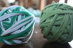 two balls of yarn sitting on top of a table next to each other, one green and the other white