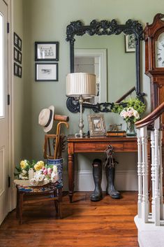 a room with a mirror, chair and clock on the wall next to a wooden table