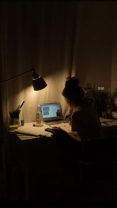 a person sitting at a desk in front of a laptop computer with a lamp on it