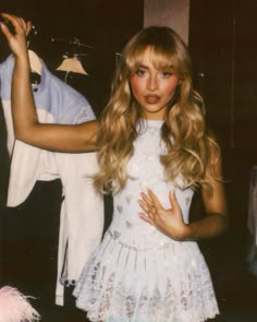 a young woman standing next to a stuffed horse and clothes on a hanger in a room