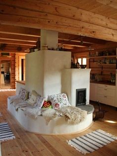 a living room filled with furniture and a fire place in the middle of a wooden floor