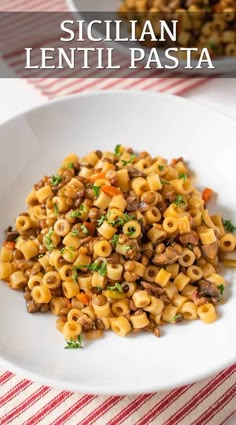 a white plate topped with pasta covered in meat and veggies next to a red and white table cloth