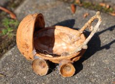 an old toy car made out of walnuts sitting on the ground next to some grass