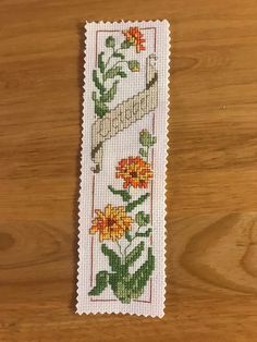 a cross - stitch bookmark with flowers on it sitting on top of a wooden table