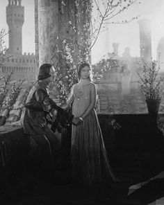 an old black and white photo of two women standing next to each other on a balcony