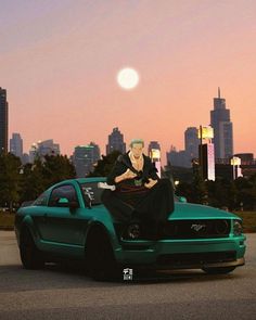 a woman sitting on the hood of a green car in front of a city skyline