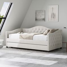 a white day bed sitting under a window next to a table and chair in a room