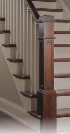 an empty staircase with wooden handrails next to a white wall and brown stairs