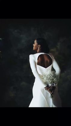 a woman in a white dress holding a bouquet of flowers and looking off into the distance