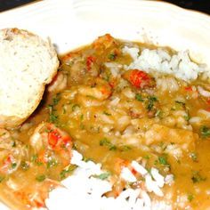 a white plate topped with shrimp and rice next to a piece of bread on top of a table