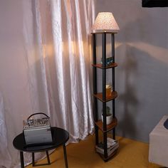 a lamp sitting on top of a wooden shelf next to a table with a laptop