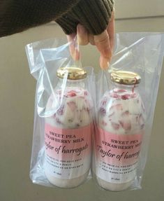 two bottles of strawberry milk are wrapped in plastic and being held by someone's hand