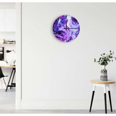 a white wall with a purple clock on it and a table in the foreground