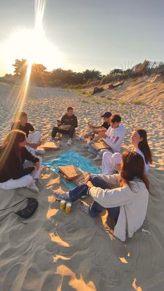 a group of people sitting on top of a sandy beach next to each other in the sand