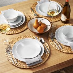 the table is set with plates, silverware and pears in bowls on it